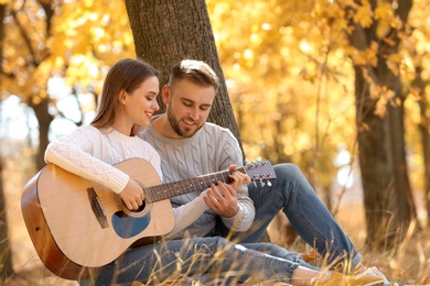 Photo of Young couple with guitar in autumn park