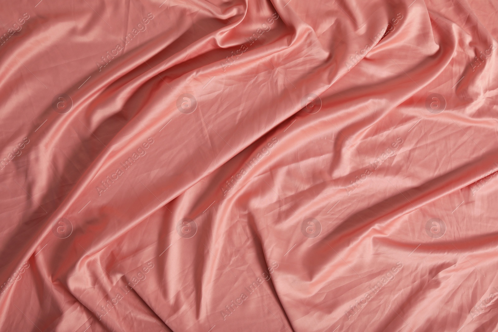 Photo of Crumpled coral fabric as background, top view