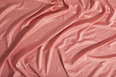 Photo of Crumpled coral fabric as background, top view