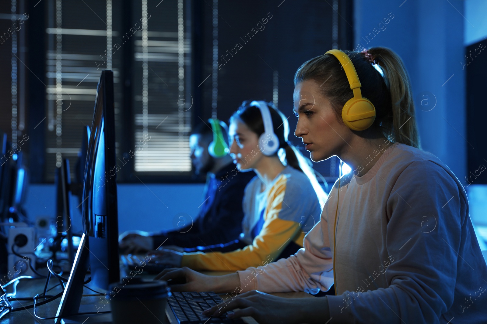 Photo of Group of people playing video games in internet cafe