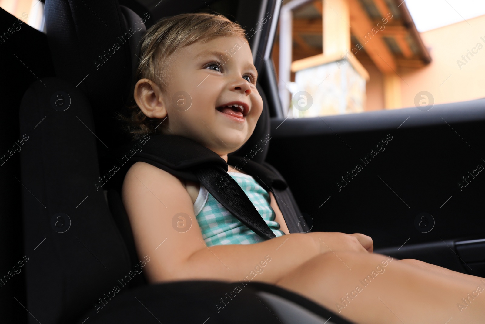 Photo of Cute little girl sitting in child safety seat inside car