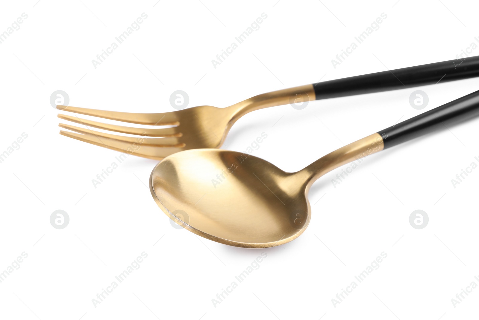 Photo of New golden fork and spoon with black handles on white background, closeup