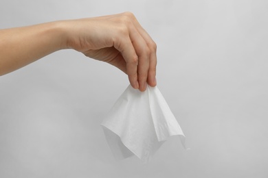 Woman holding paper tissue on light background, closeup