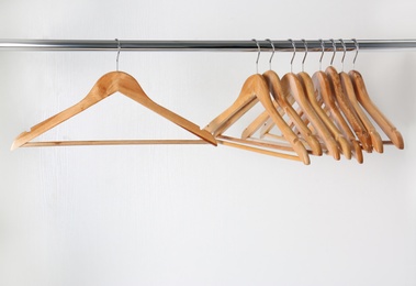 Photo of Clothes rail with wooden hangers on white background