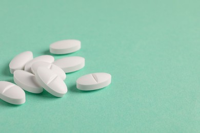 Pile of white pills on green background, closeup. Space for text