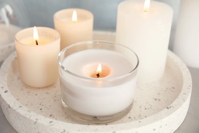 Tray with burning aromatic candles on table