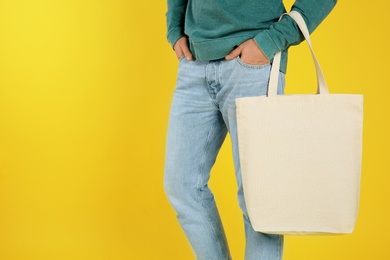 Young man holding textile bag on color background, closeup. Mockup for design