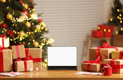 Photo of Laptop with blank screen, Christmas gifts and letters on table at home