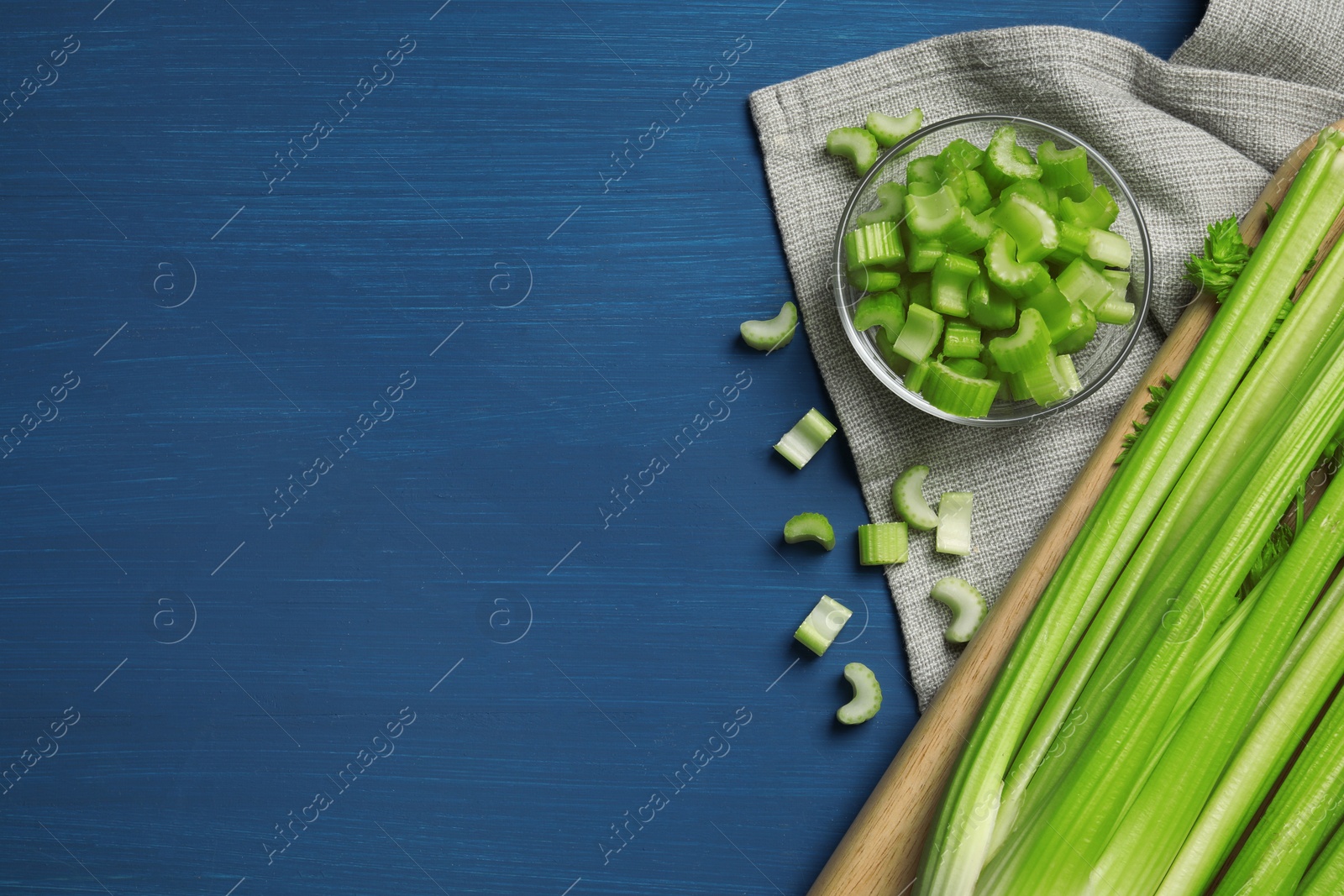 Photo of Fresh cut and whole celery on blue wooden table, top view. Space for text