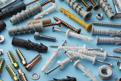 Photo of Many different fasteners and dowels on light blue background, above view