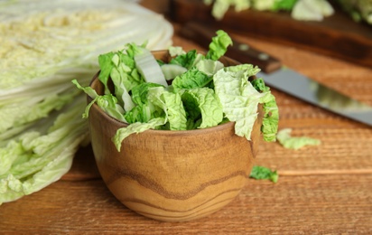 Photo of Chopped Chinese cabbage in bowl on wooden table