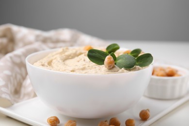 Photo of Delicious hummus with chickpeas served on white table, closeup