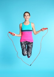 Photo of Full length portrait of young sportive woman training with jump rope on color background