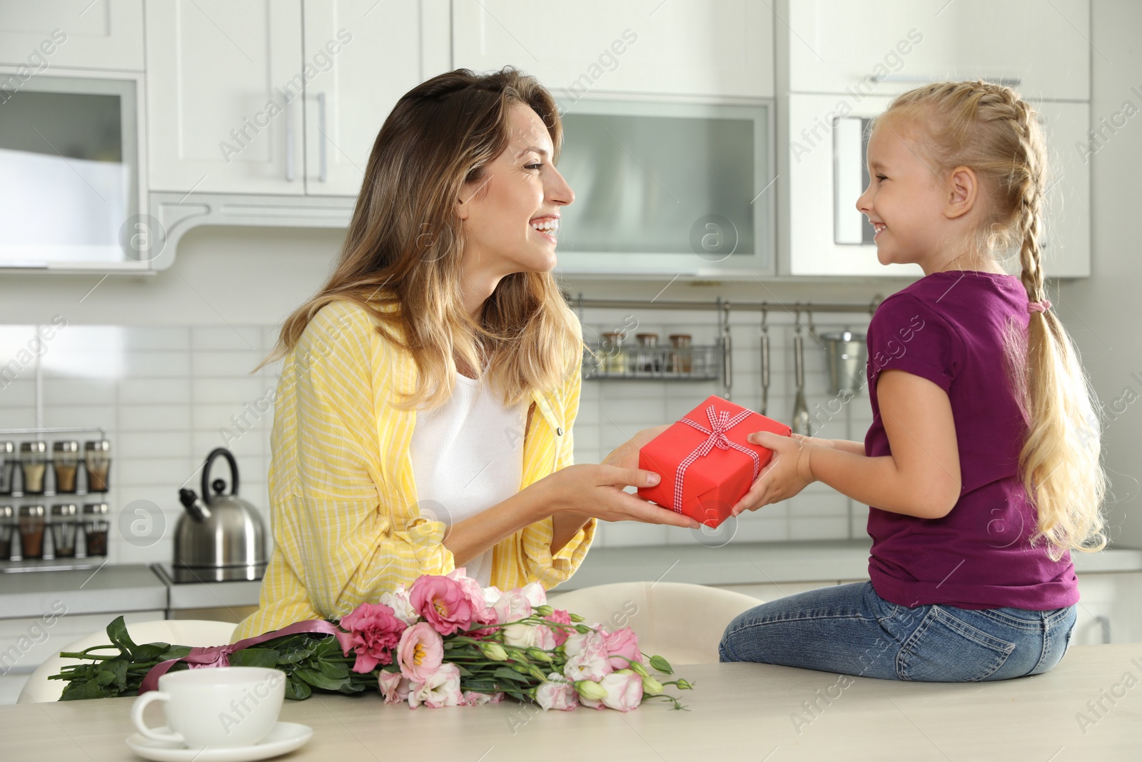 Photo of Little daughter congratulating her mom in kitchen. Happy Mother's Day