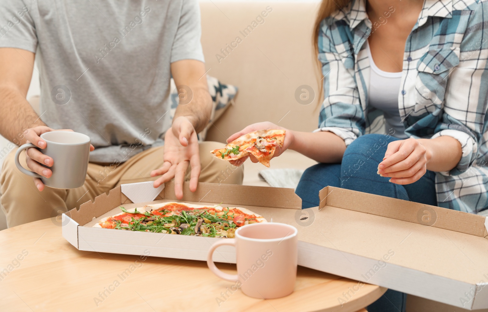 Photo of Young couple having pizza for lunch at home, closeup. Food delivery