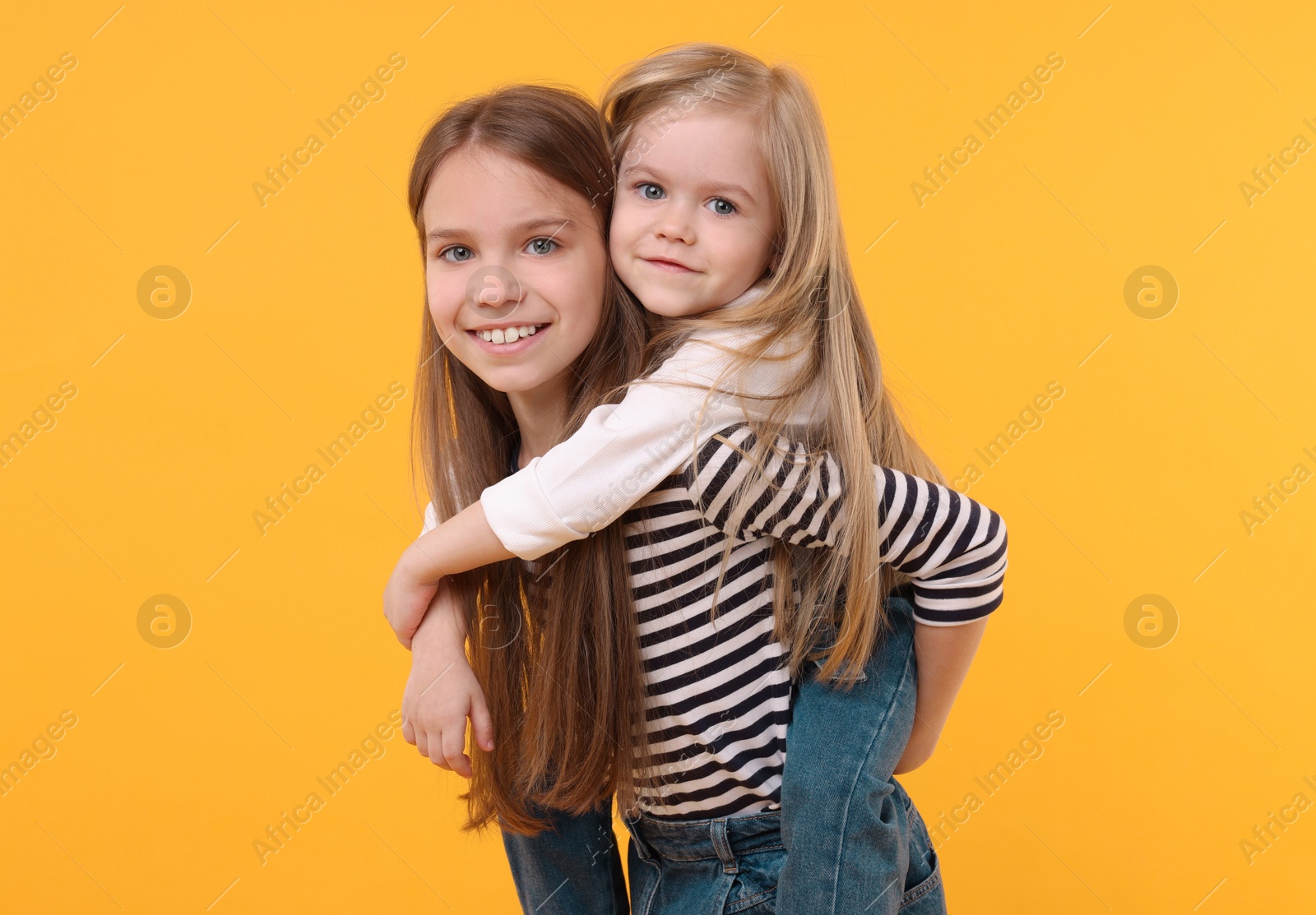 Photo of Portrait of cute little sisters on orange background