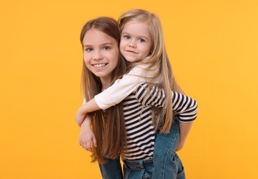 Portrait of cute little sisters on orange background