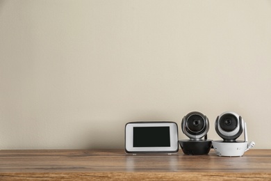 Photo of Baby monitors on wooden table, space for text. CCTV equipment