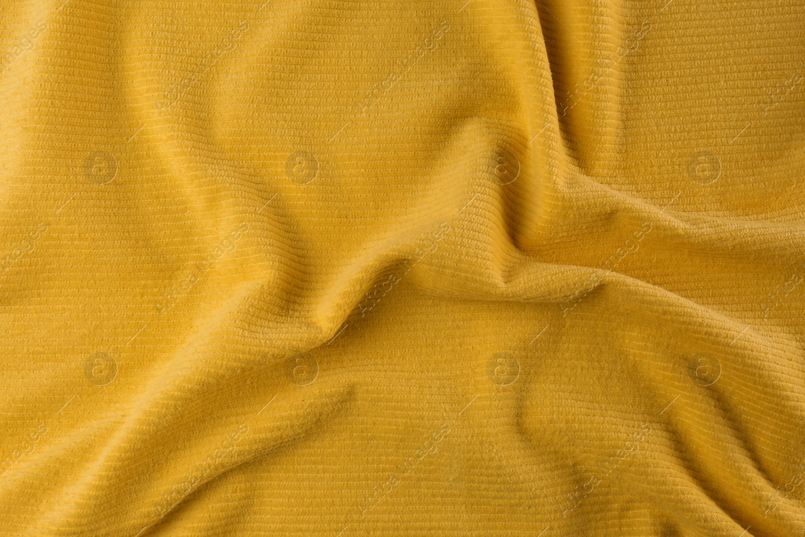 Photo of Crumpled yellow beach towel as background, top view