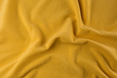 Photo of Crumpled yellow beach towel as background, top view