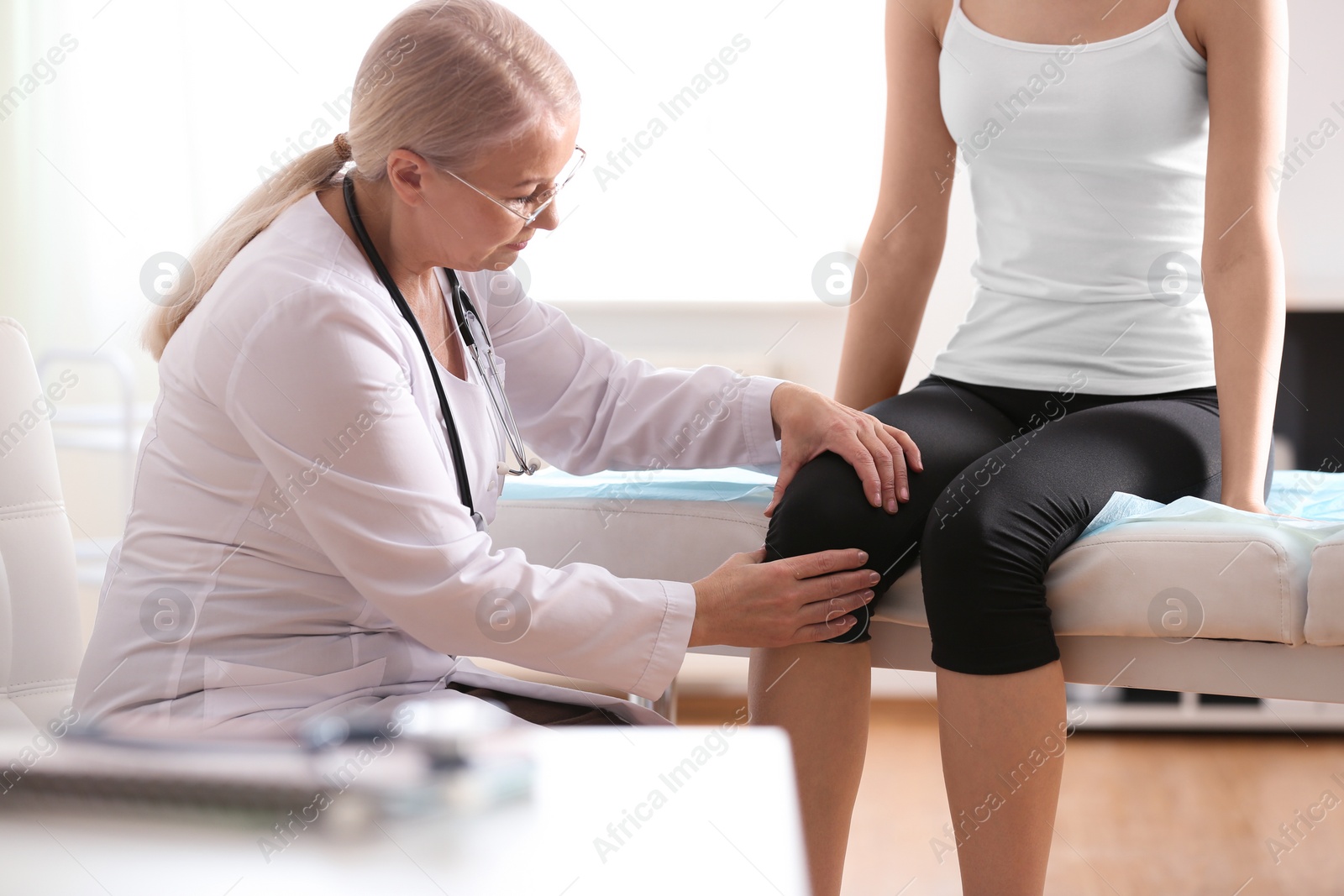 Photo of Female orthopedist examining patient's knee in clinic