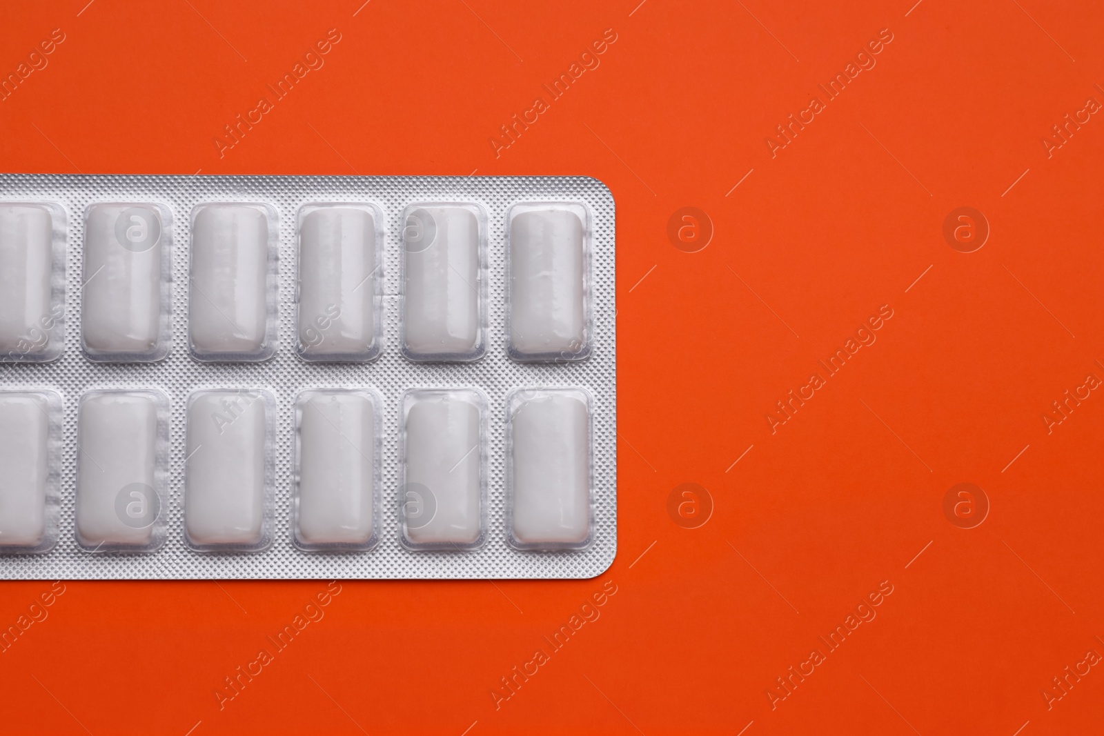 Photo of Blister with chewing gums on orange background, top view. Space for text