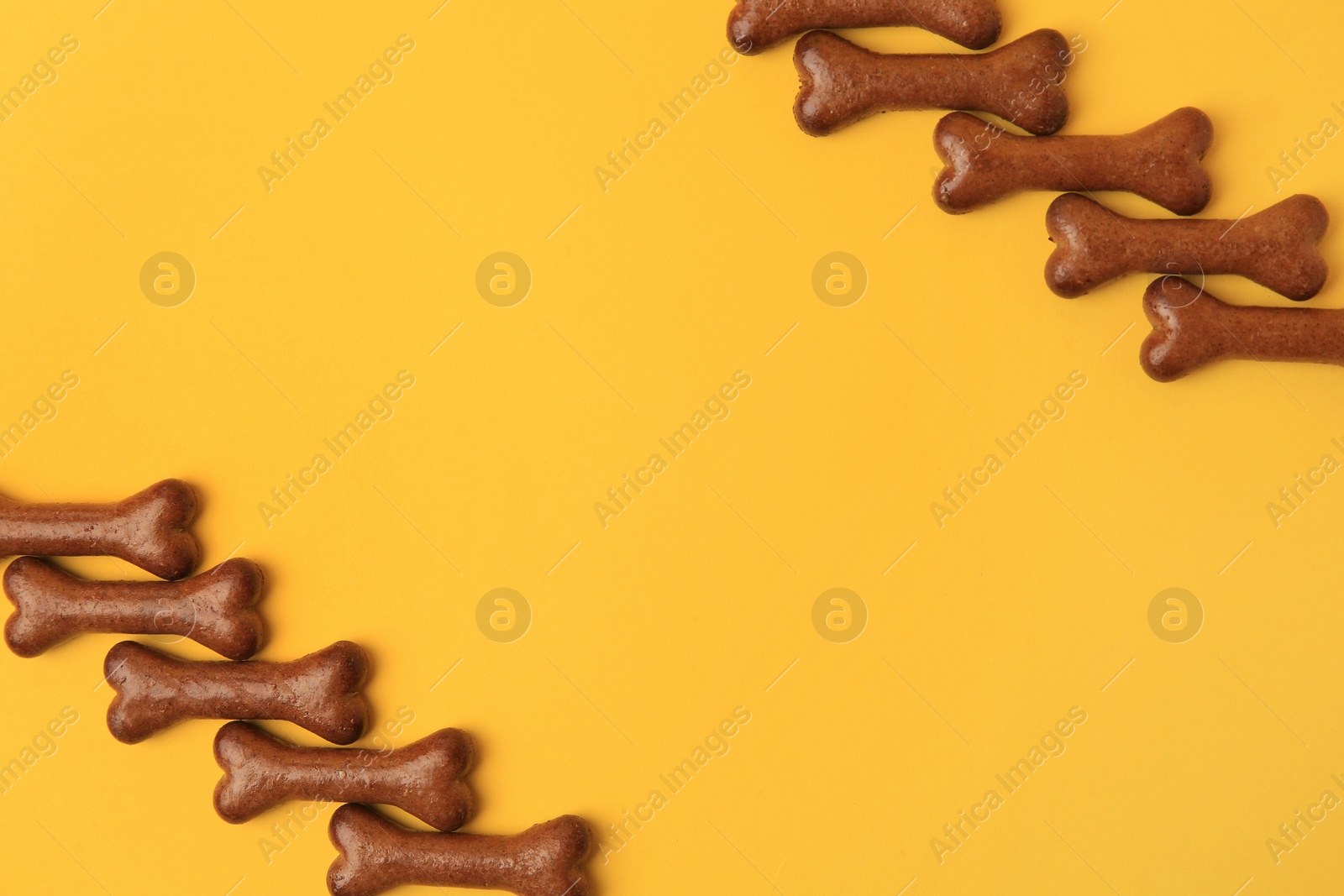 Photo of Bone shaped dog cookies on orange background, flat lay. Space for text