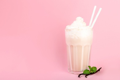 Glass with vanilla milk shake on color background