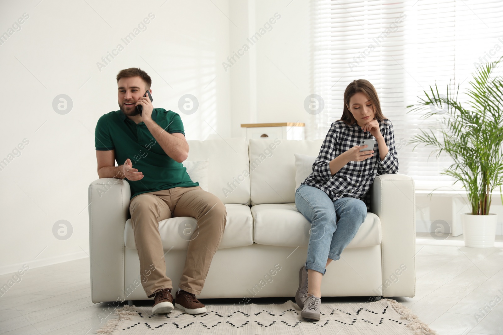 Photo of Couple addicted to smartphones ignoring each other at home. Relationship problems