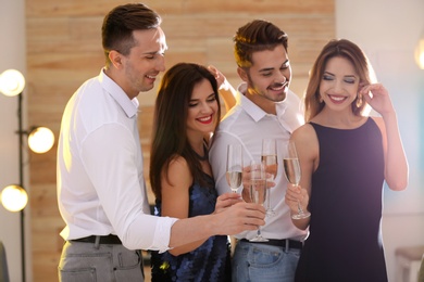 Photo of Friends clinking glasses with champagne at party indoors