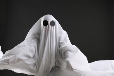 Creepy ghost. Person covered with white sheet on black background