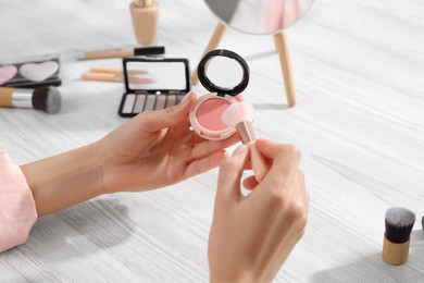 Photo of Woman with blusher and brush at dressing table, closeup