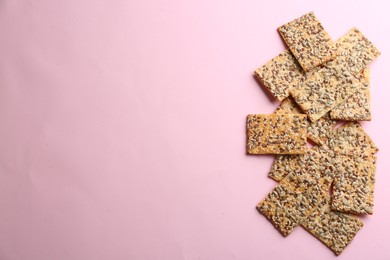 Photo of Delicious crackers on pink background, flat lay. Space for text