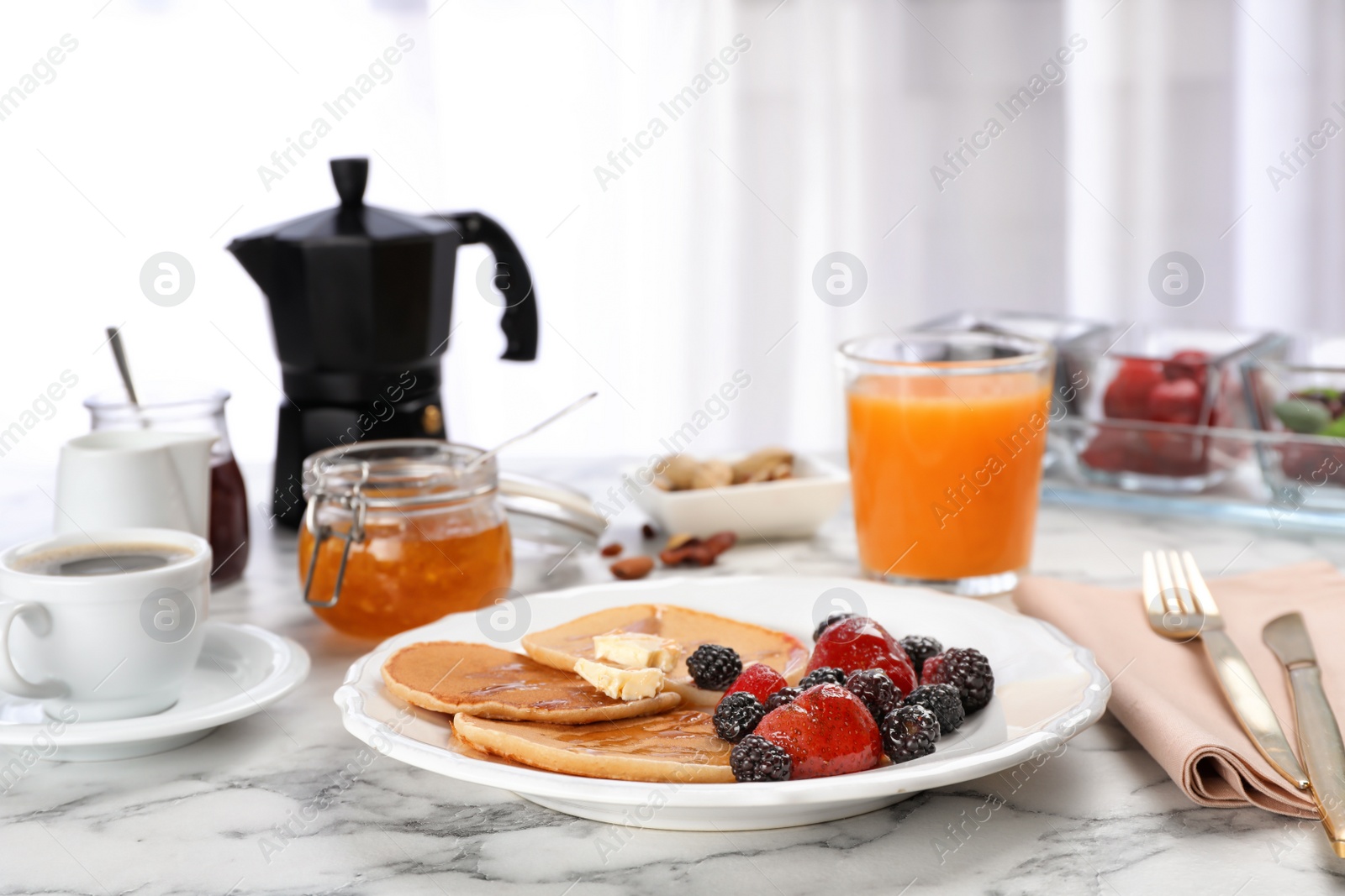 Photo of Delicious pancakes with berries and butter served for breakfast on table