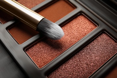 Photo of Beautiful eye shadow palette and brush as background, closeup