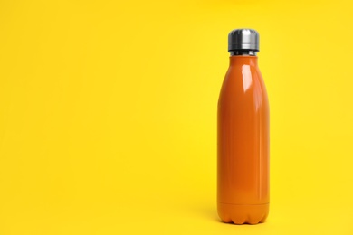 Photo of Stylish thermo bottle on yellow background, space for text