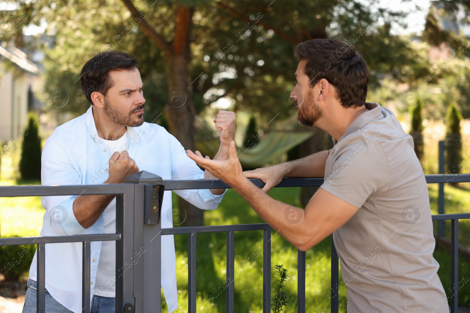 Photo of Angry neighbours having argument near fence outdoors