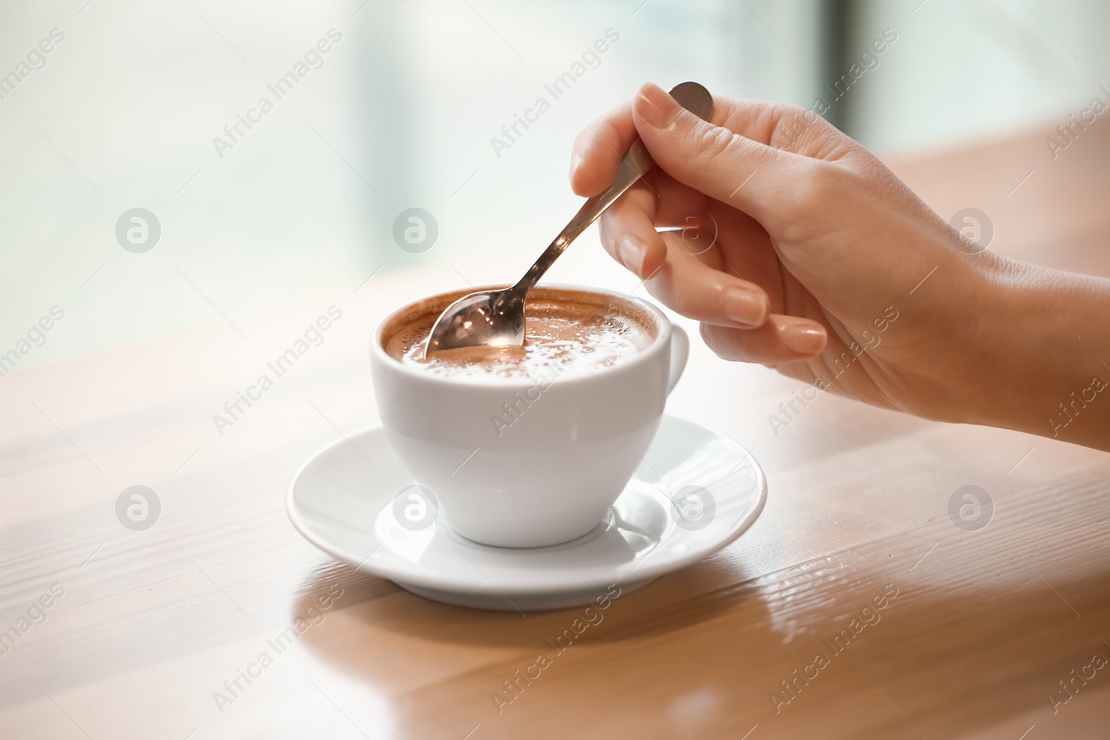 Photo of Woman with cup of aromatic coffee at wooden table