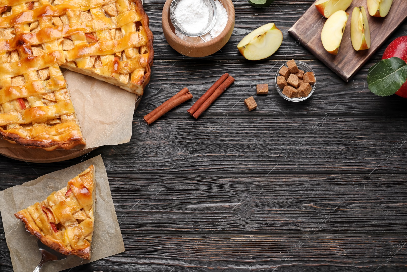 Photo of Traditional apple pie and ingredients on black wooden table, flat lay. Space for text