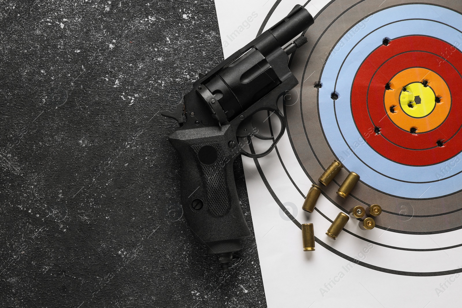 Photo of Shooting target, handgun and bullets on dark gray table, top view. Space for text