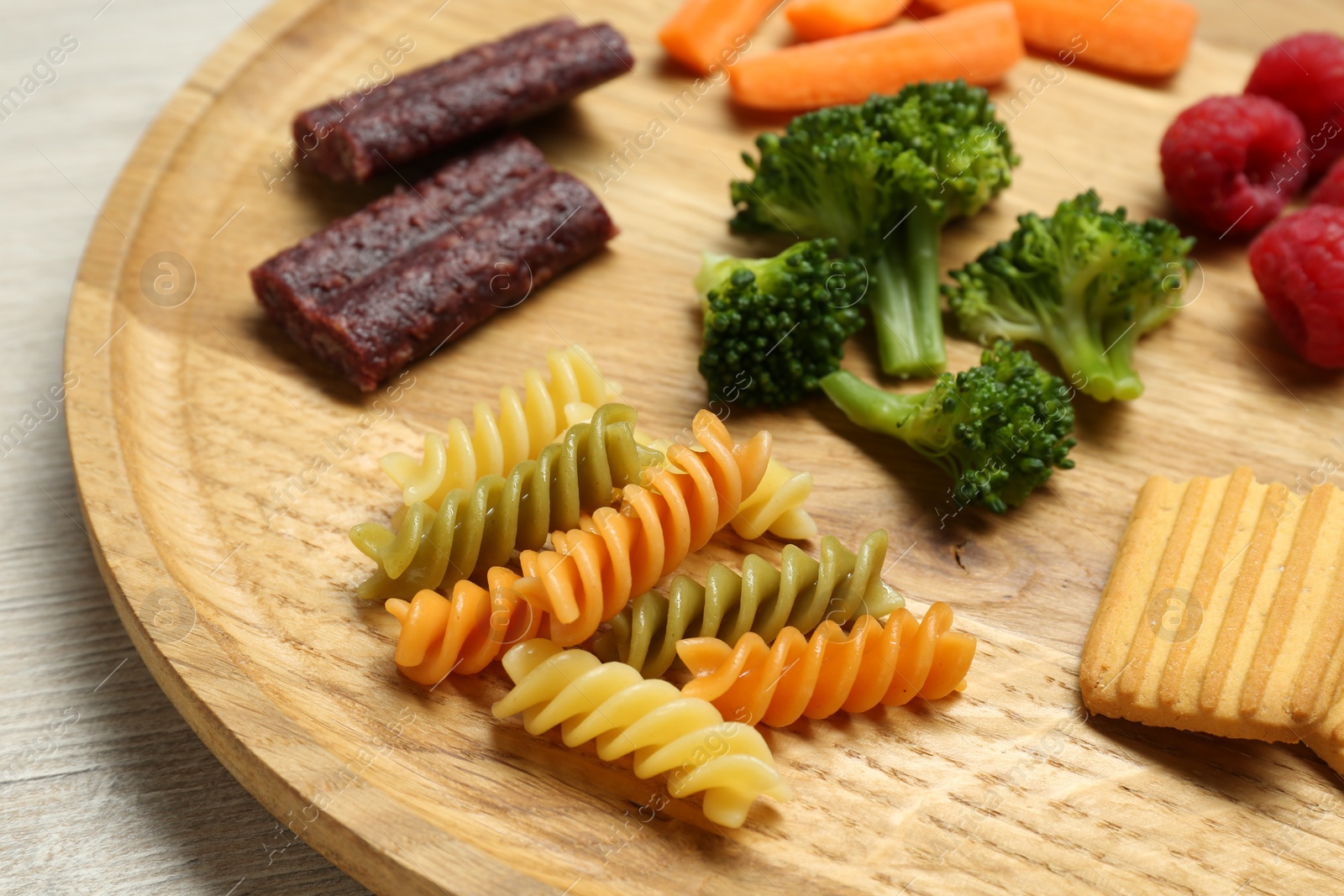 Photo of Wooden board with different finger foods for baby on table, closeup