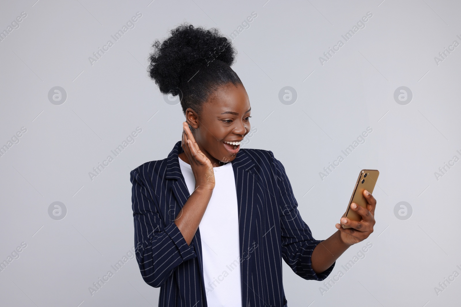 Photo of Happy young woman using smartphone on light grey background