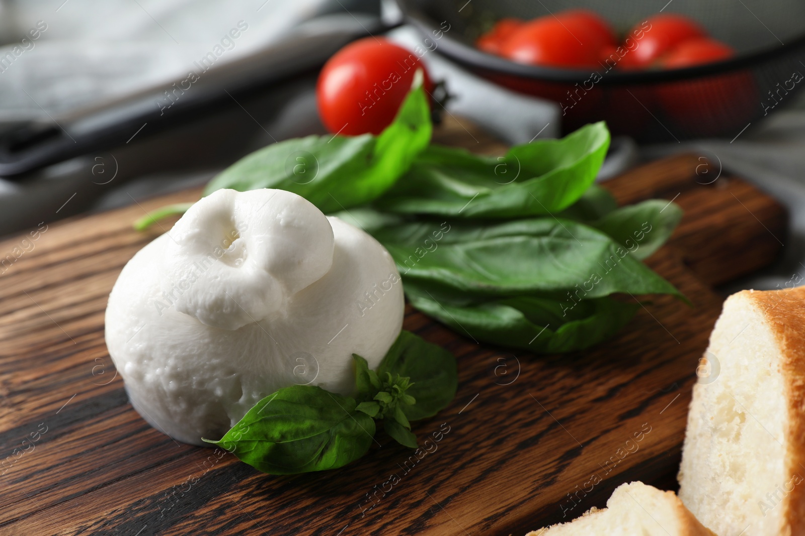 Photo of Delicious burrata cheese with basil on wooden board, closeup