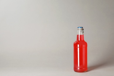 Bottle of alcoholic drink on grey background. Space for text