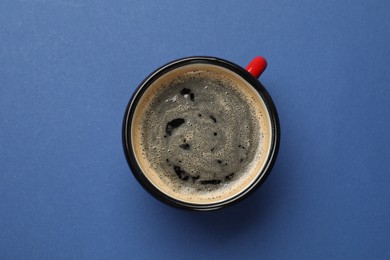 Fresh coffee in cup on blue background, top view