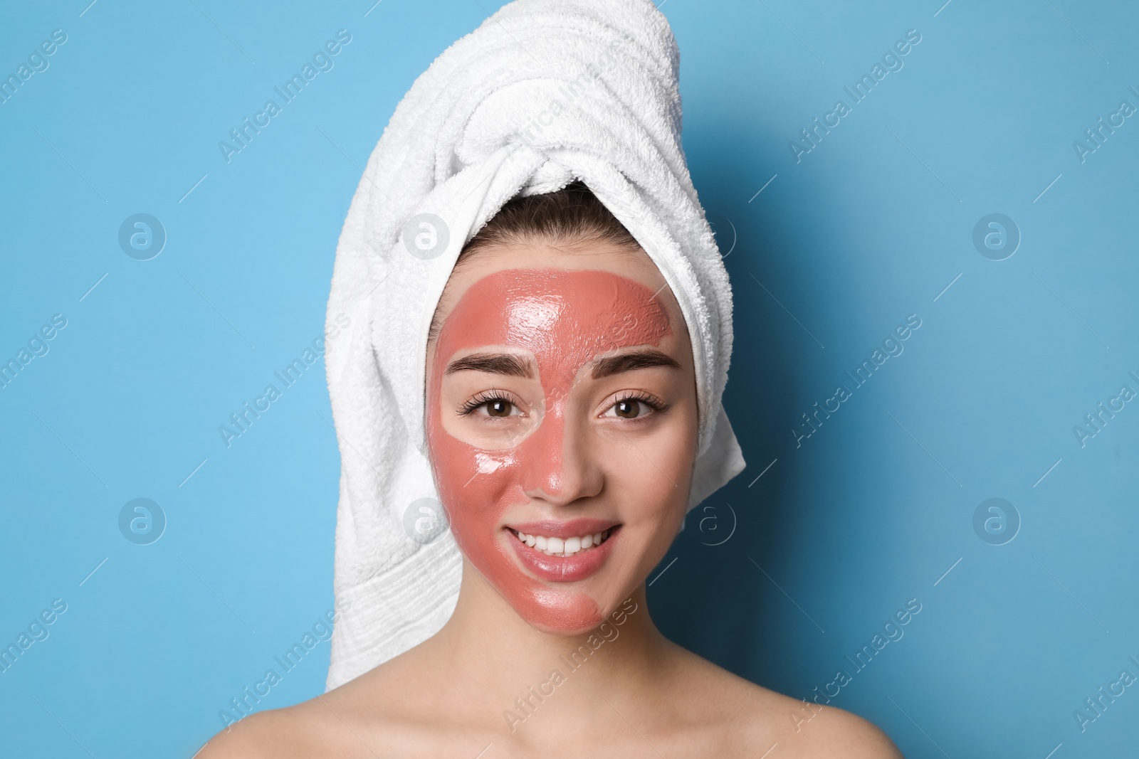 Photo of Woman with pomegranate face mask on light blue background