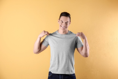 Young man in grey t-shirt on color background. Mockup for design