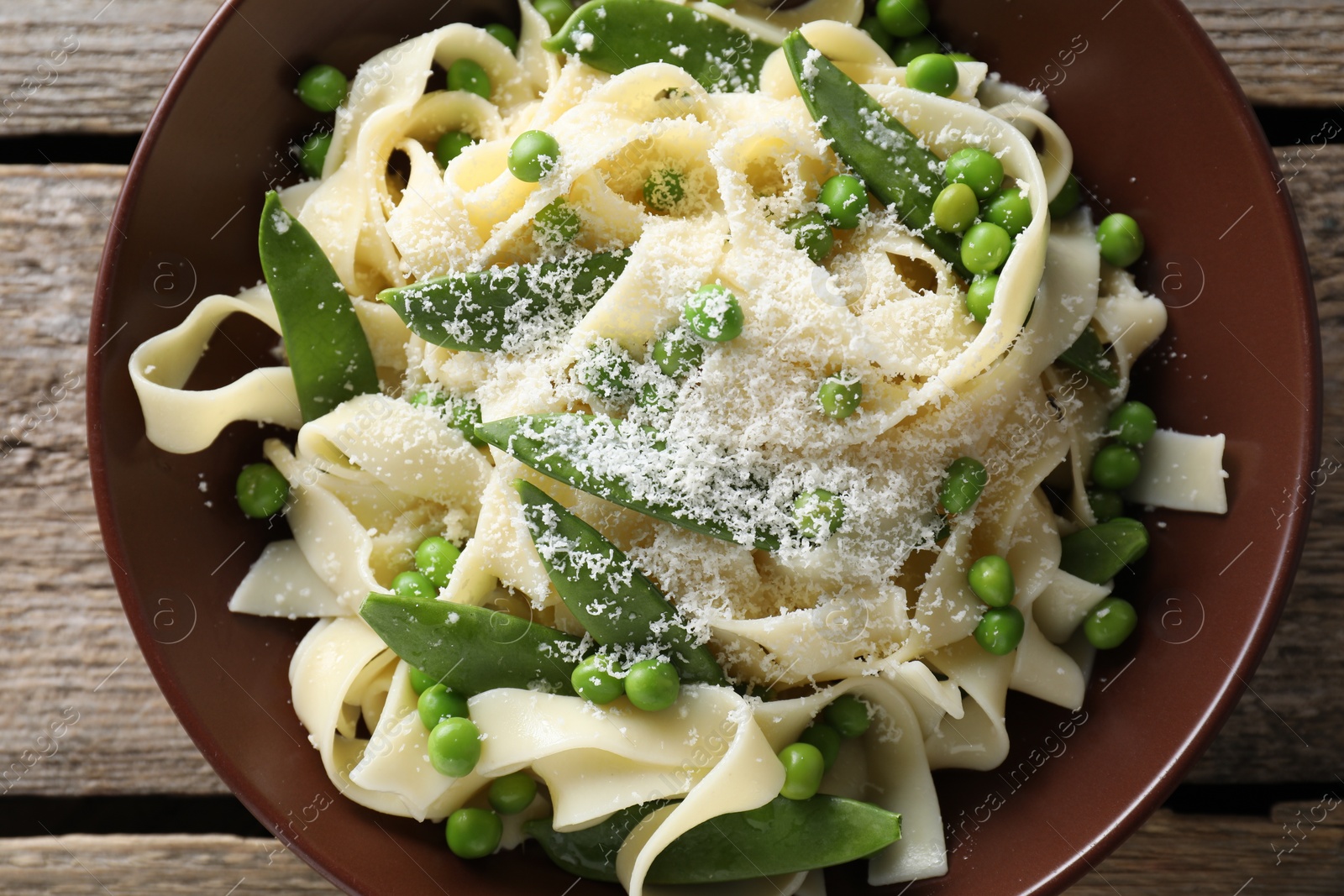 Photo of Delicious pasta with green peas and cheese on wooden table