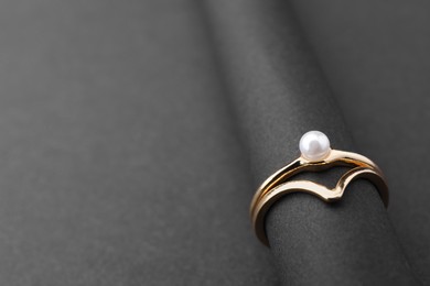 Photo of Elegant pearl rings on black background, closeup. Space for text