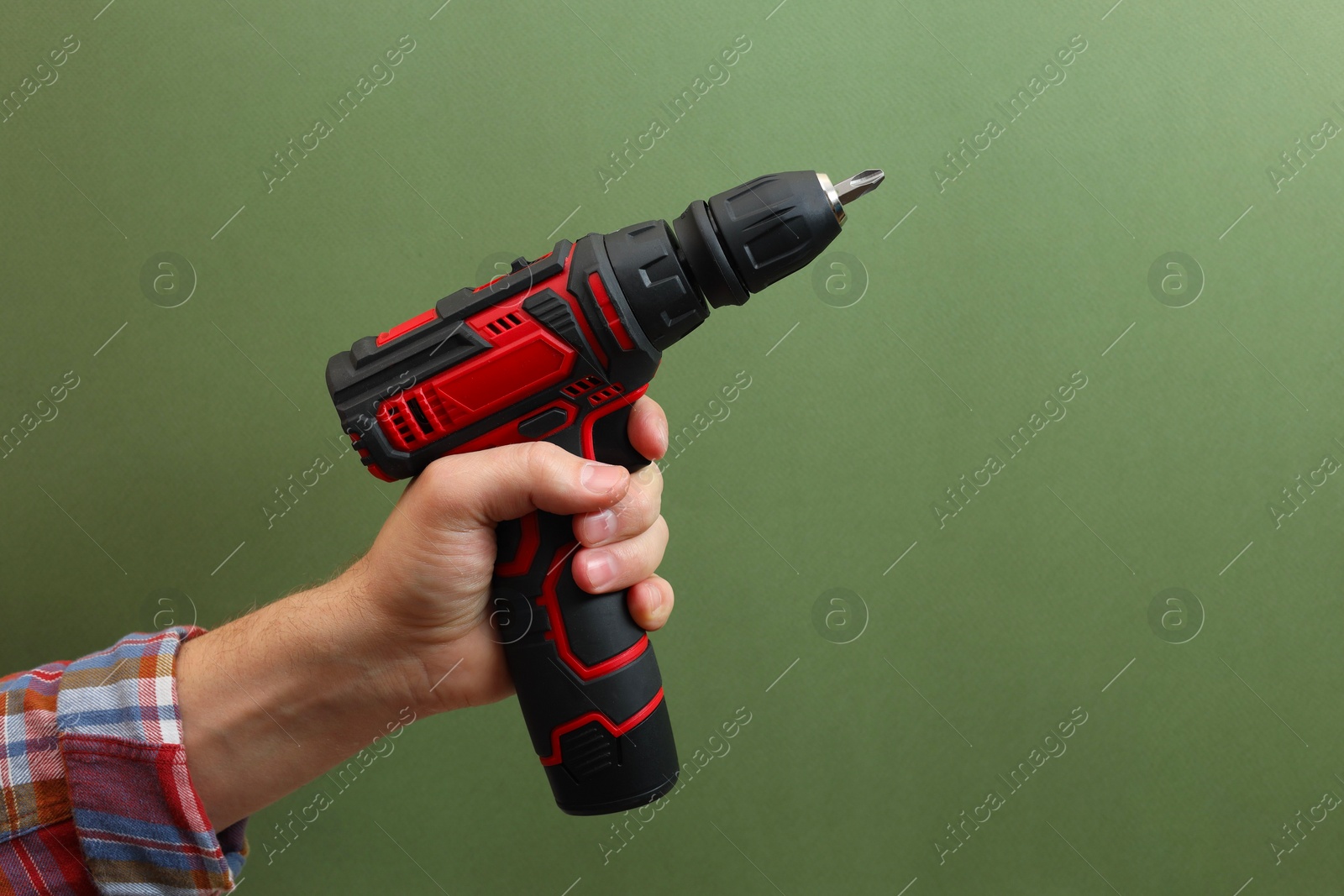 Photo of Handyman holding electric screwdriver on pale green background, closeup